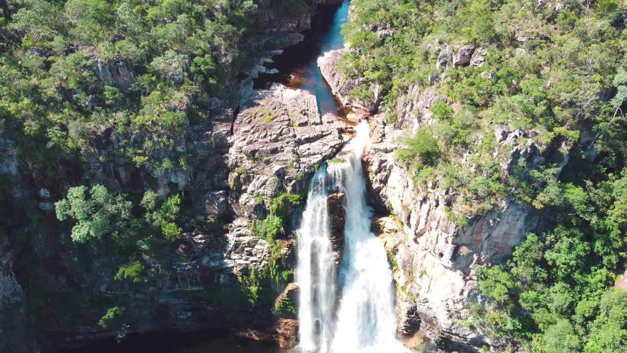 Beautiful waterfall with a rainbow in native forest aerial view. Black river 80 meters fall in Veadeiros, Goias, Brazil