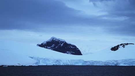 Antarctica-Winter-Mountains-Coastal-Scenery,-Dramatic-Clouds-and-Sky-in-Cold-Dark-Blue-Landscape-with-Glaciers-and-Ocean-Sea-Water-on-Coast,-Antarctic-Peninsula-Seascape-in-Moody-Atmospheric-Scene