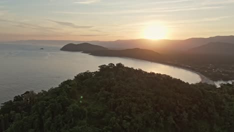 aerial view zoom in sun on juquehy bay at sunset sunrise with mountains and trees