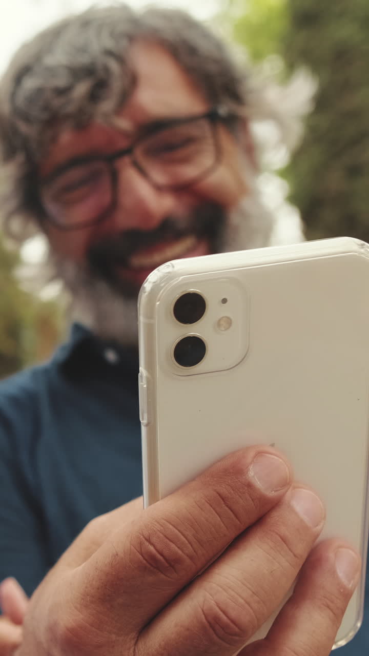 Uomo felice che tiene in mano uno smartphone all'aperto e sorride