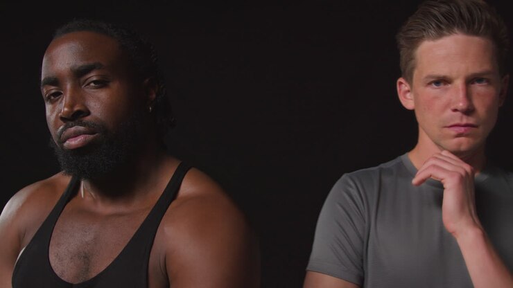 Close Up Studio Portrait Of Serious Determined Male Athletes Training In Fitness Clothing Shot Against Black Background