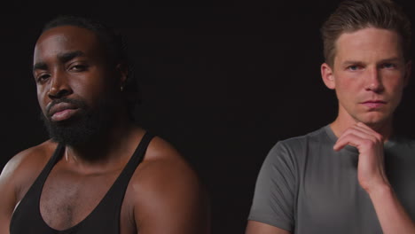 close up studio portrait of serious determined male athletes training in fitness clothing shot against black background