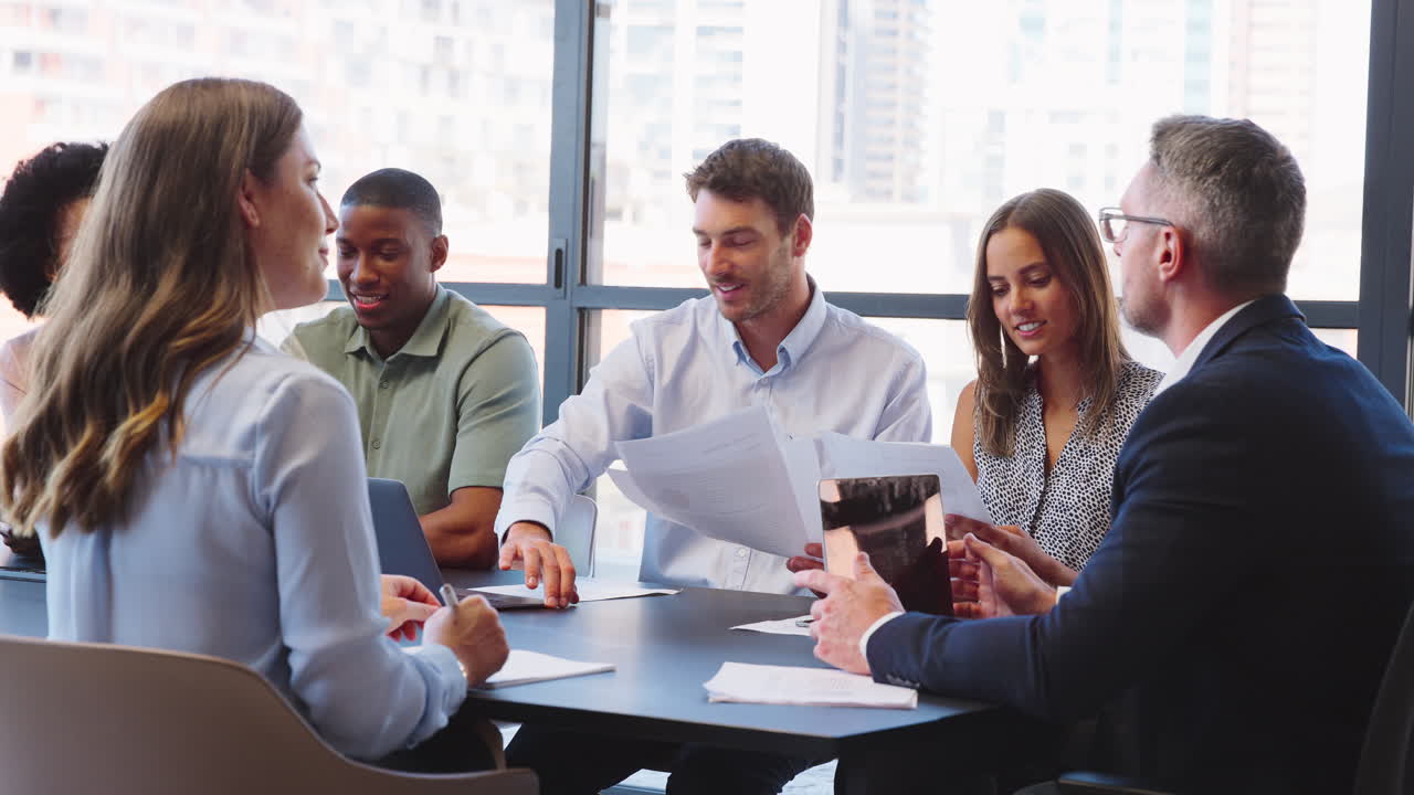 Multi-Cultural Business Team Meeting Around Office Boardroom Table With ...