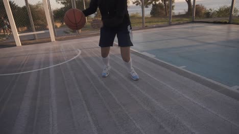 female basketball player in morning light on professional court running with ball