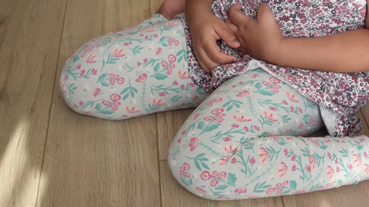 niño sentado en el suelo con dolor de estómago