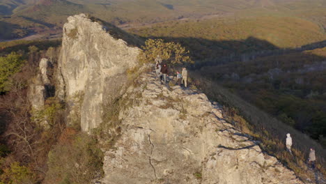 People-hiking-and-reaching-the-top-of-the-cliff-with-epic-view-of-river-estuary-beneath-them,-on-the-sunset