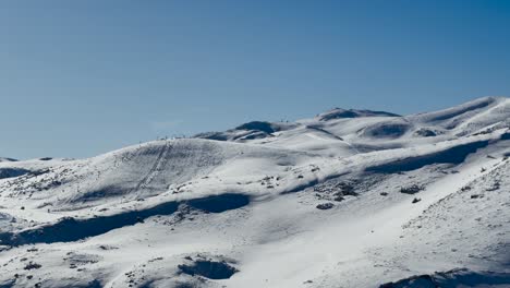 a scenic view of a snow-covered mountain ski resort with smooth slopes and clear blue skies