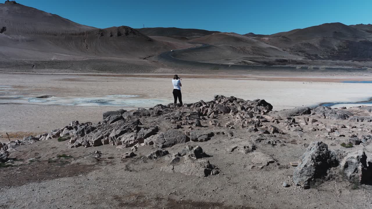 Donna in piedi davanti a una strada che sale sulle montagne dell'Islanda vicino a Namafjall.