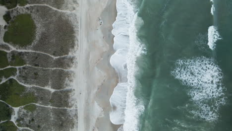 aerial looking directly down on lapping waves on shoreline of wrightsville beach, north carolina