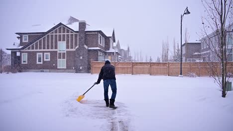 man cleaning snow from driveway in winter after a snow storm