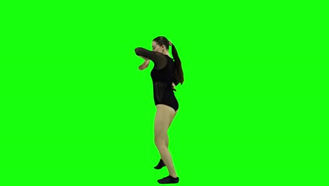 a view from the side to an amazing female dancer dancing in front of a green screen