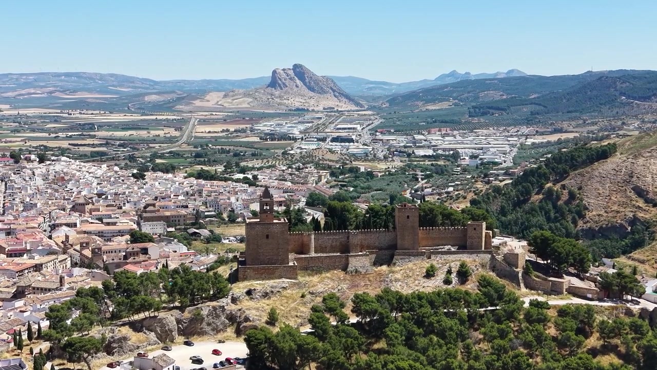 Vista aérea con dron de la Alcazaba de Antequera dominando la ciudad de Antequera, España, con la icónica montaña Peña de los Enamorados al fondo