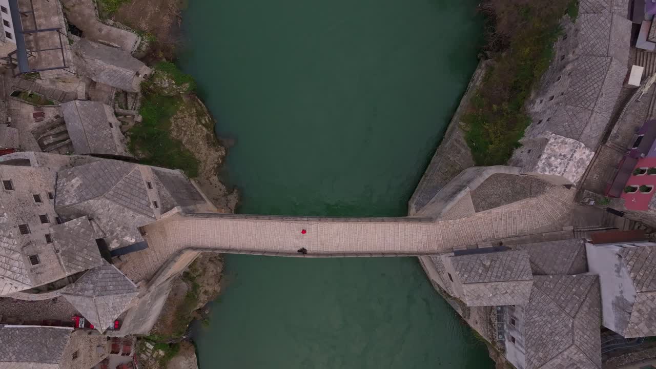 Toma aérea de Stari Most resplandeciendo bajo la suave luz del amanecer dorado sobre el río