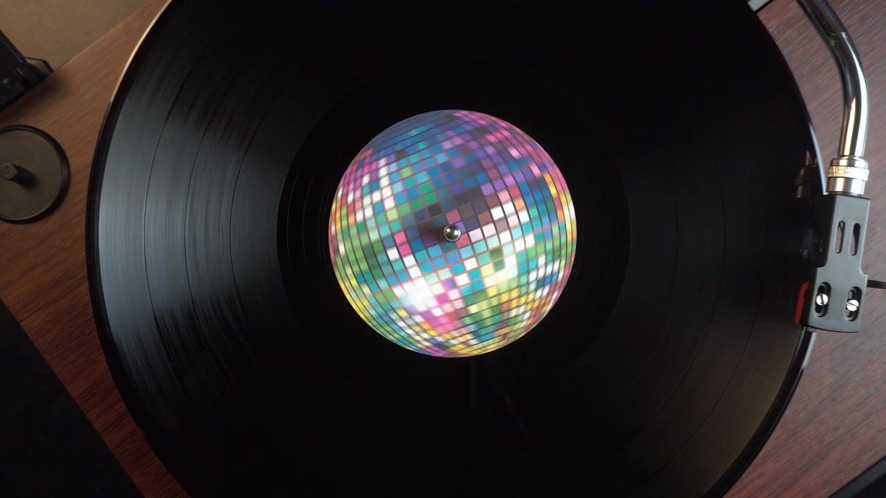 Iniciando la reproducción de un disco de vinilo con una pegatina de bola de discoteca, vista cenital.