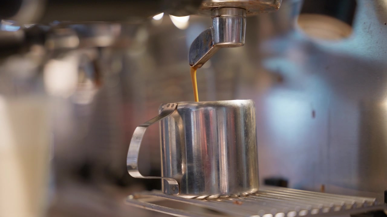 Primo piano di caffè espresso fresco appena estratto da una macchina da caffè professionale. Filmato girato in un ambiente di ospitalità aeroportuale, ideale per il settore delle bevande e della caffetteria.