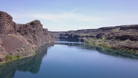 low flight over deep blue lake with vertical cliffs in arid landscape