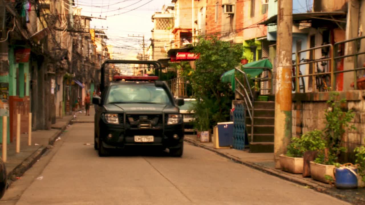 Black truck with police in the back patrols the favela looking for drug gangs