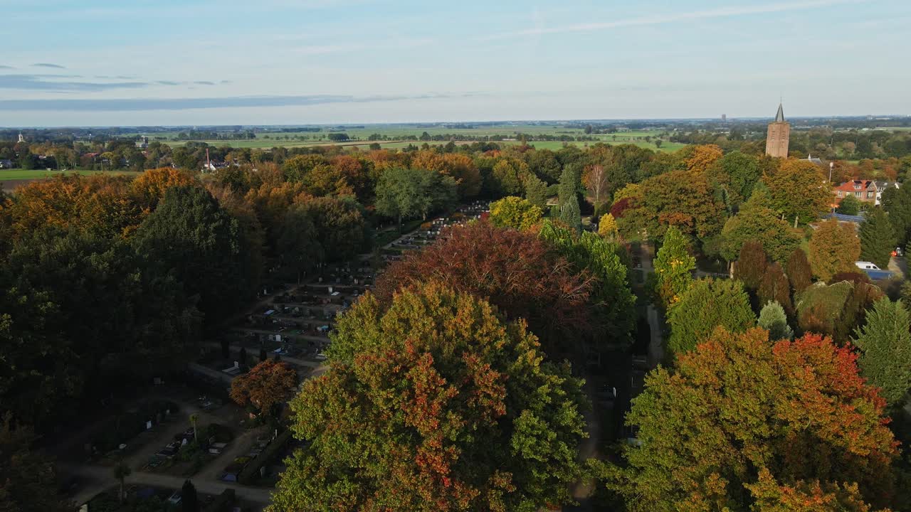 Jib down of a beautiful cemetery surrounded by lush green trees in a small Dutch town on a sunny autumn day