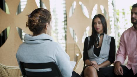 Woman-with-plait-sitting-on-chair-and-talking-to-colleagues