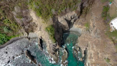 drone view of water hitting rock on fernando de noranha island, brazil, paradise, sea