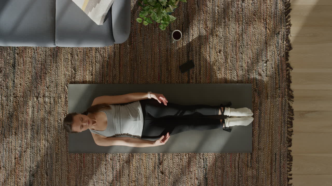 vista superior de una mujer de yoga practicando la postura del cadáver ejerciendo un estilo de vida saludable entrenando en casa sobre una colchoneta de ejercicios disfrutando de la meditación de atención plena.