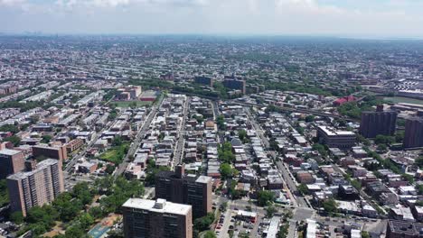 an aerial shot over brooklyn. the drone hovers high in the sky as the camera tilts up from a ground view of cars driving by on the parkway below. the camera then reveals white clouds and blue skies