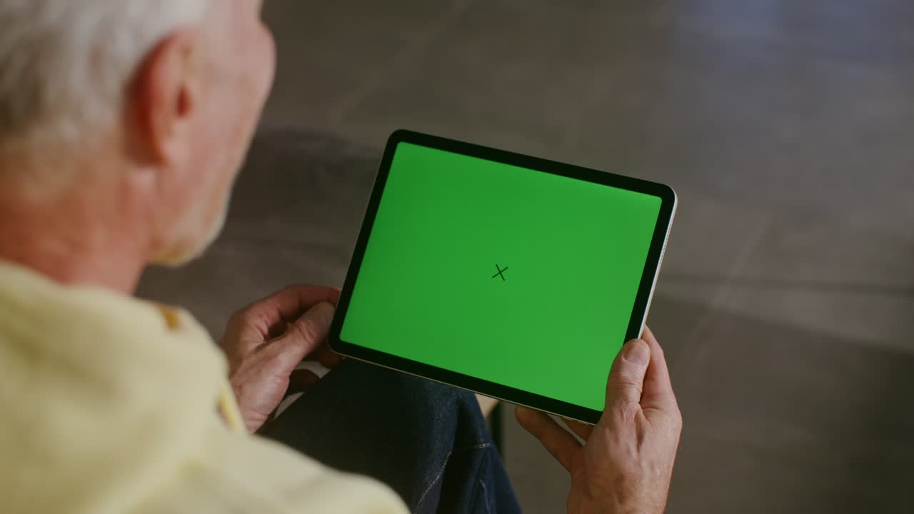 hombre mayor usando una tableta con pantalla verde