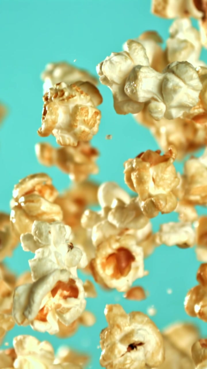 Popcorn al caramello che volano al rallentatore su sfondo turchese