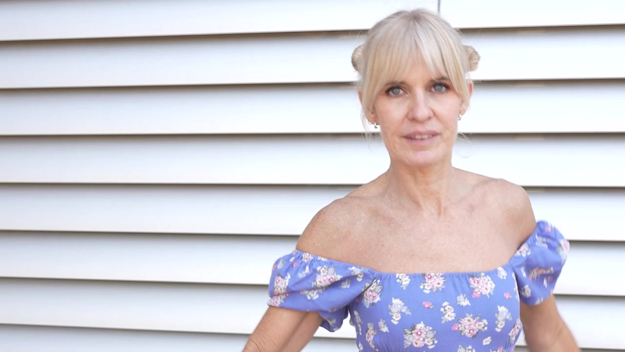 Donna elegante in abito floreale irradia sicurezza e femminilità all'aperto in un bellissimo ritratto.