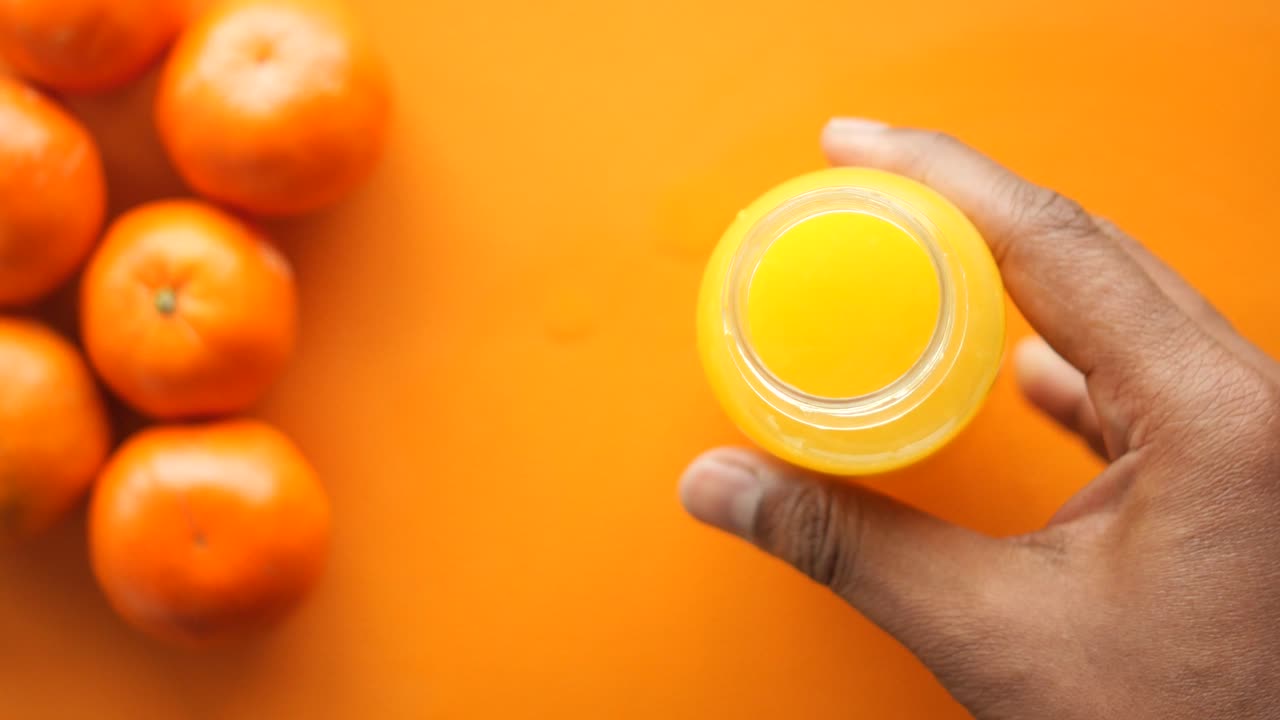 손은 배경에 오렌지와 함께 오렌지 주스의 병을 열고