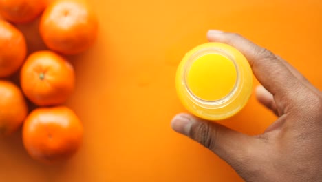 mano abriendo una botella de jugo de naranja con naranjas en el fondo