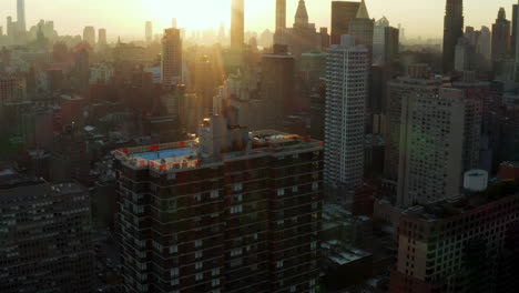 Aerial-shot-of-apartment-building-with-rooftop-swimming-pool.-high-rise-buildings-in-town,-view-against-setting-sun.-Manhattan,-New-York-City,-USA