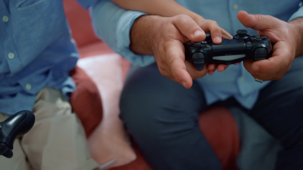 niño y hombre manos jugando videojuegos con gamepads. familia divirtiéndose en casa