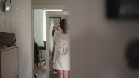 woman in white robe looking in mirror