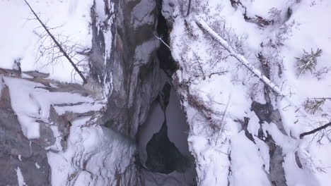 antena vertical del estrecho cañón del río de invierno con agua corriente debajo