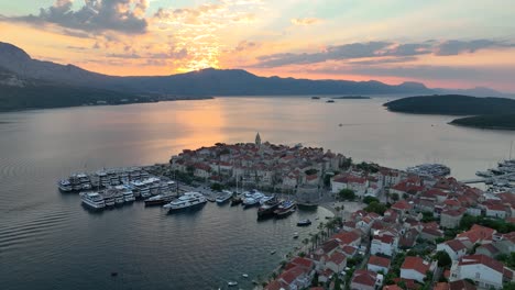 aerial drone shot flying towards korcula old town in croatia, during sunrise over the mountains