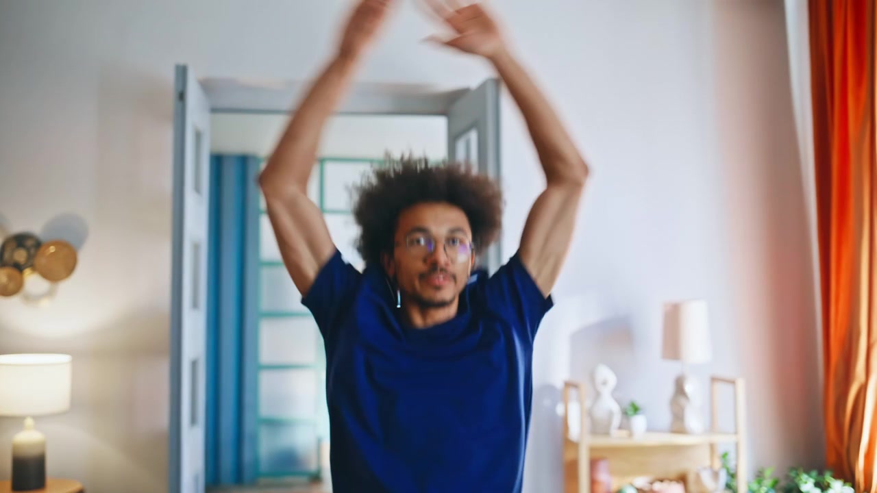 Multietnisk par danser i stuen. Glad ungt par træner hjemme sammen