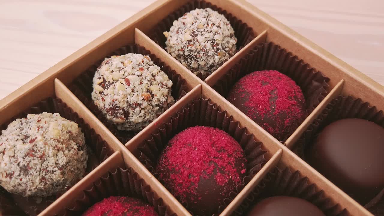 fabricación de cajas de regalos de caramelos de chocolate movimiento de cámara de primer plano extremo. chocolates variados confitería en fondo blanco cámara lenta, deslizador