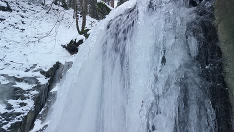 Drone-Volando-Cerca-De-Una-Cascada-Helada-En-Un-Bosque-En-Suiza