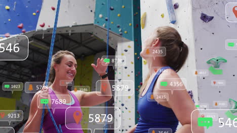 animación de iconos de los medios sobre dos mujeres caucásicas felices dando cinco en la pared de escalada