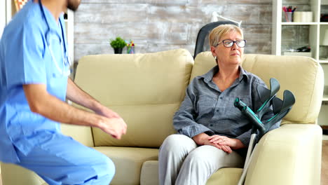 male nurse talking with old woman suffering of parkinson