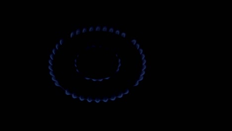 a close-up of the blue flame of a gas burner in a home kitchen, which burns and slowly goes out on a black background. a conceptual symbol of the energy crisis. top view. 4k.