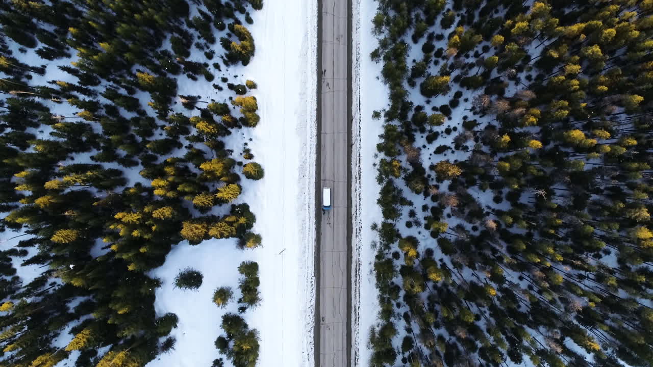 Veduta aerea a volo d'uccello di un camion bianco che si muove su una strada diritta in un freddo paesaggio invernale