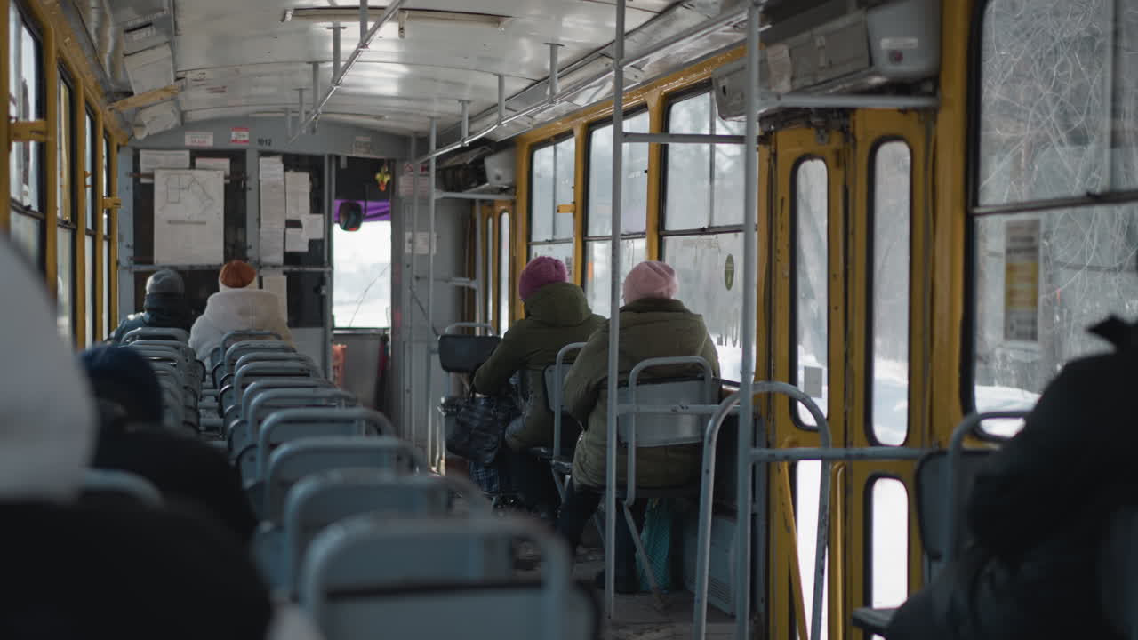 yellow minibus driving along city street lined with shops, pedestrians, and signboards under bright daylight, with tangled overhead cables adding urban character to busy commercial scene