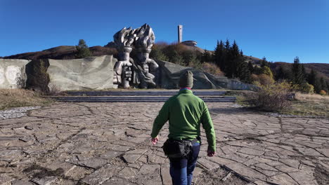 solitary traveler approaching iconic buzludzha monument, emblematic communist era structure nestled among balkan mountain landscape, symbolizing forgotten socialist architectural heritage