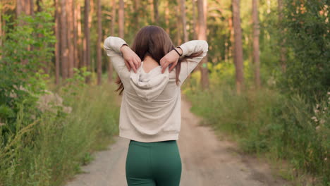 a woman walks on a path through a forest