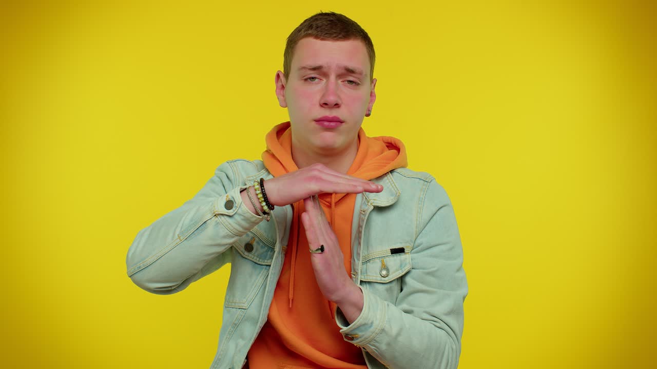 피곤한 진지한 십대 남자가 타임아웃 제스처, 제한 또는 정지 표지판을 보여줍니다. 압력이 없습니다. 더 많은 시간이 필요합니다.