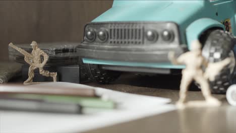 collection of toy soldiers, a tank, and a truck on a desk