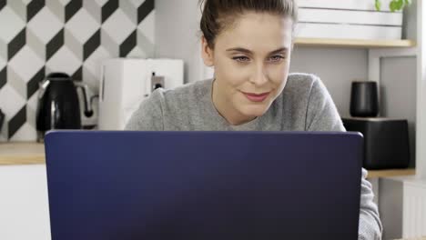 mujer joven usando una computadora portátil en su cocina