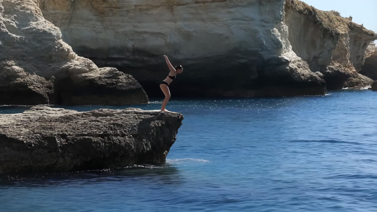 Person cliff diving into the clear blue sea